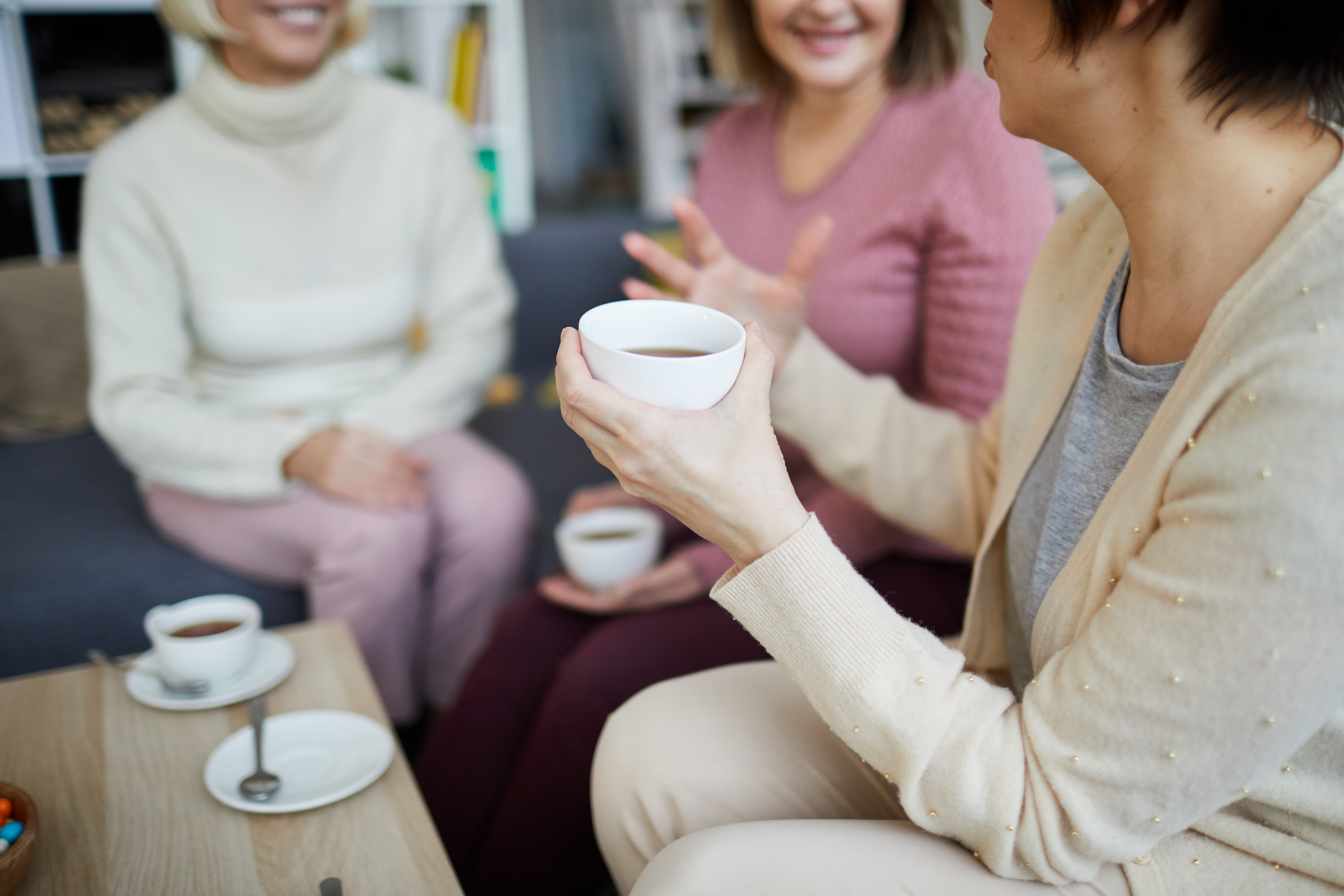 three adults drinking coffee and chatting