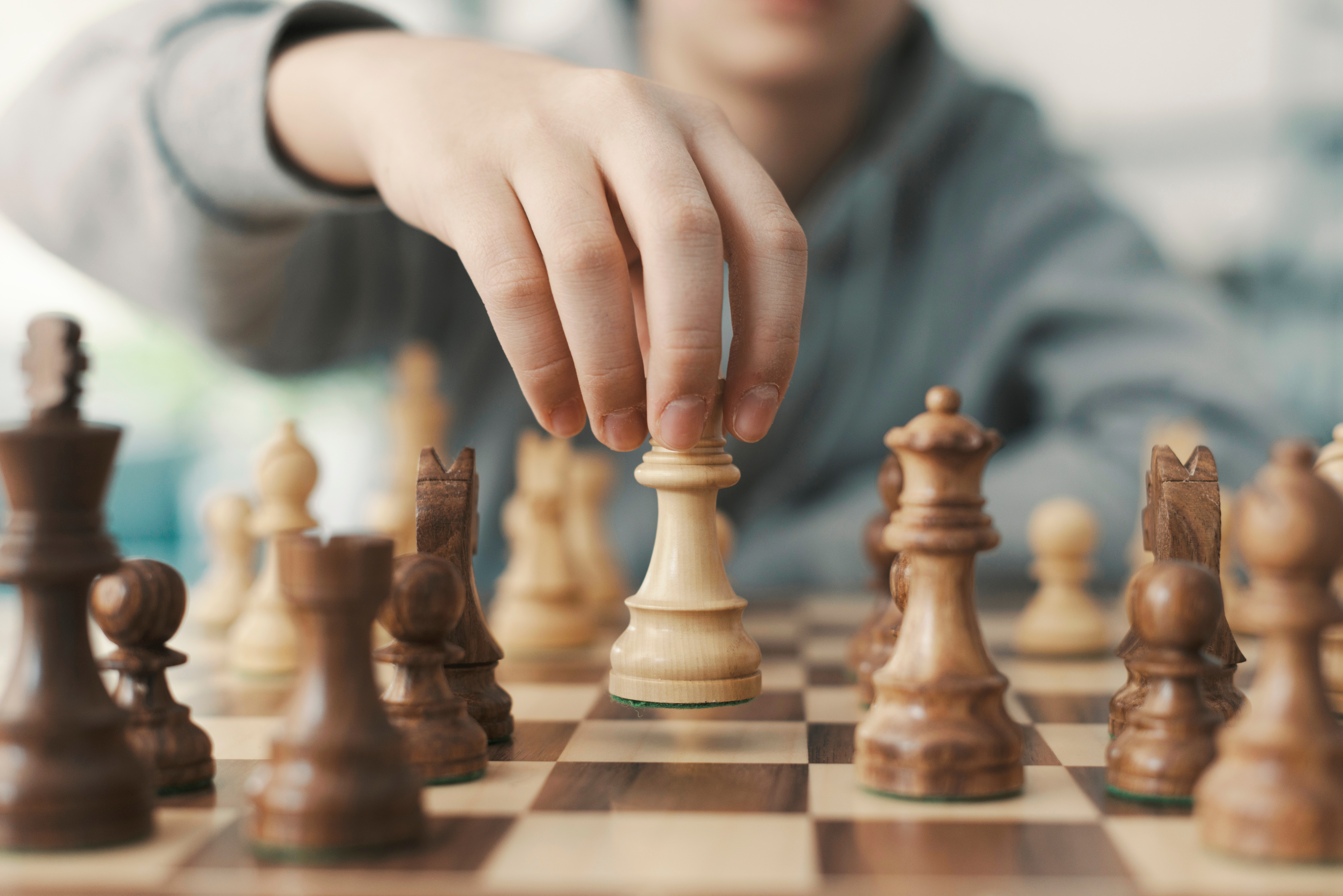 chess board with a hand moving a chess piece