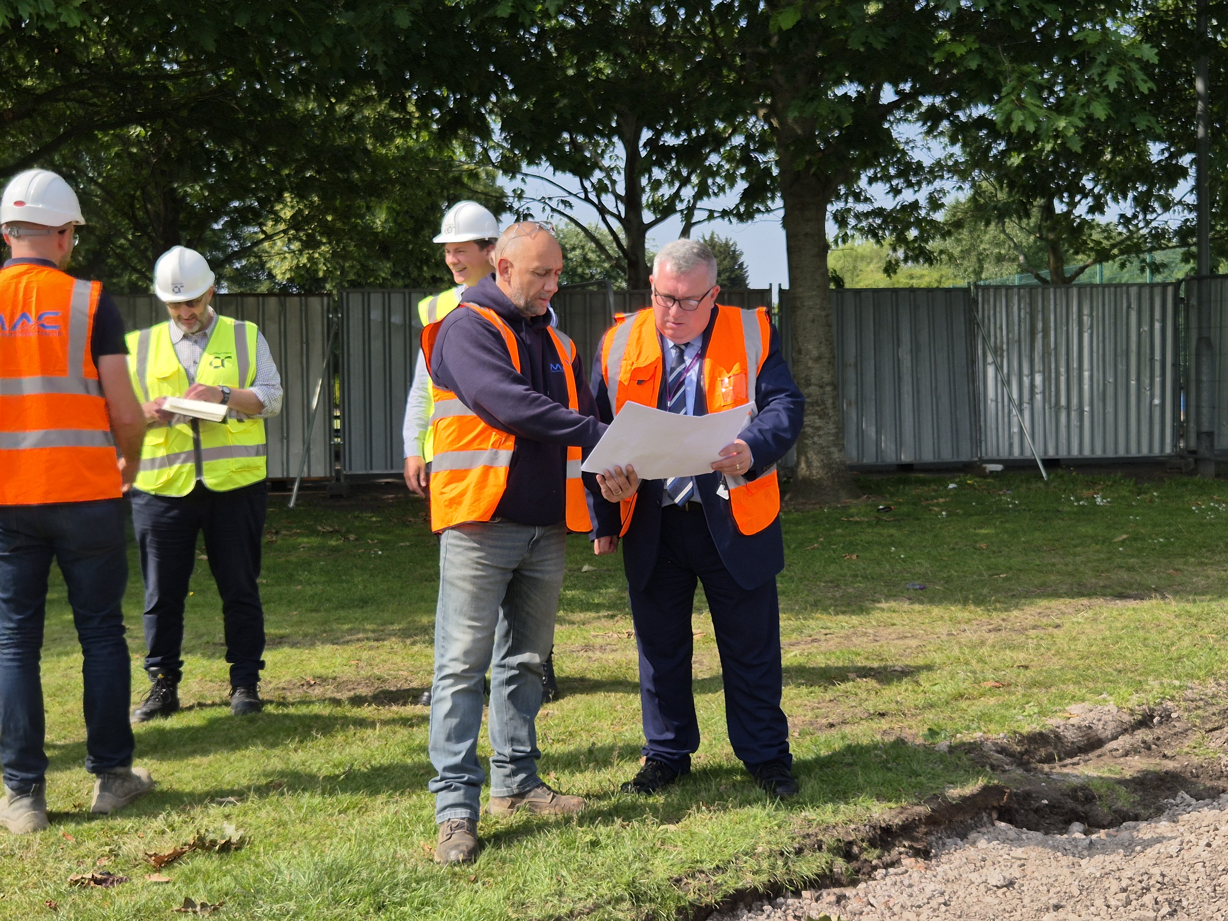 a group in high vis look at plan drawings in a park