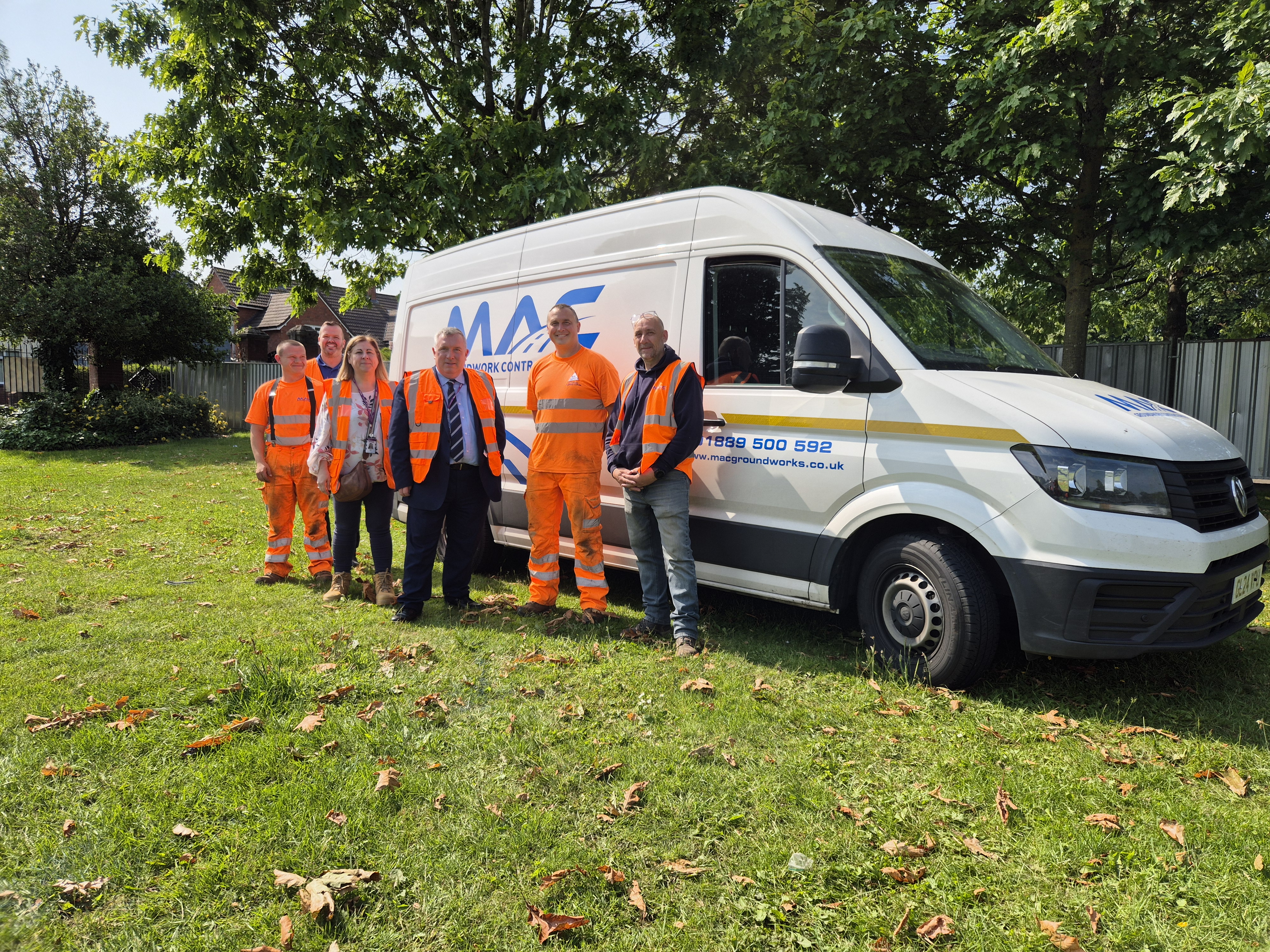 A group of people stand in front of a van wearing high vis jackets