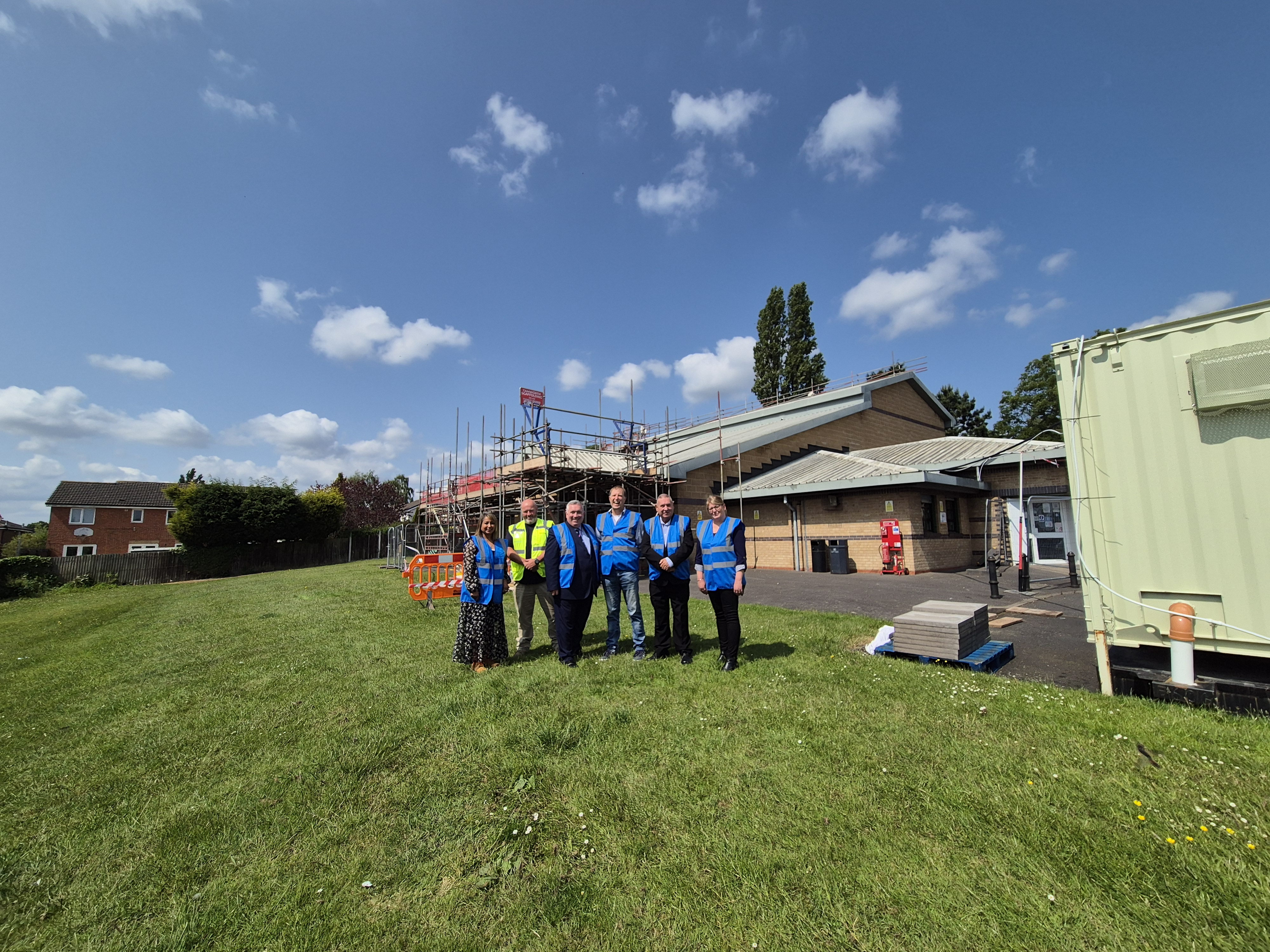 A group in high vis jackets stand in front of a building with scaffolding