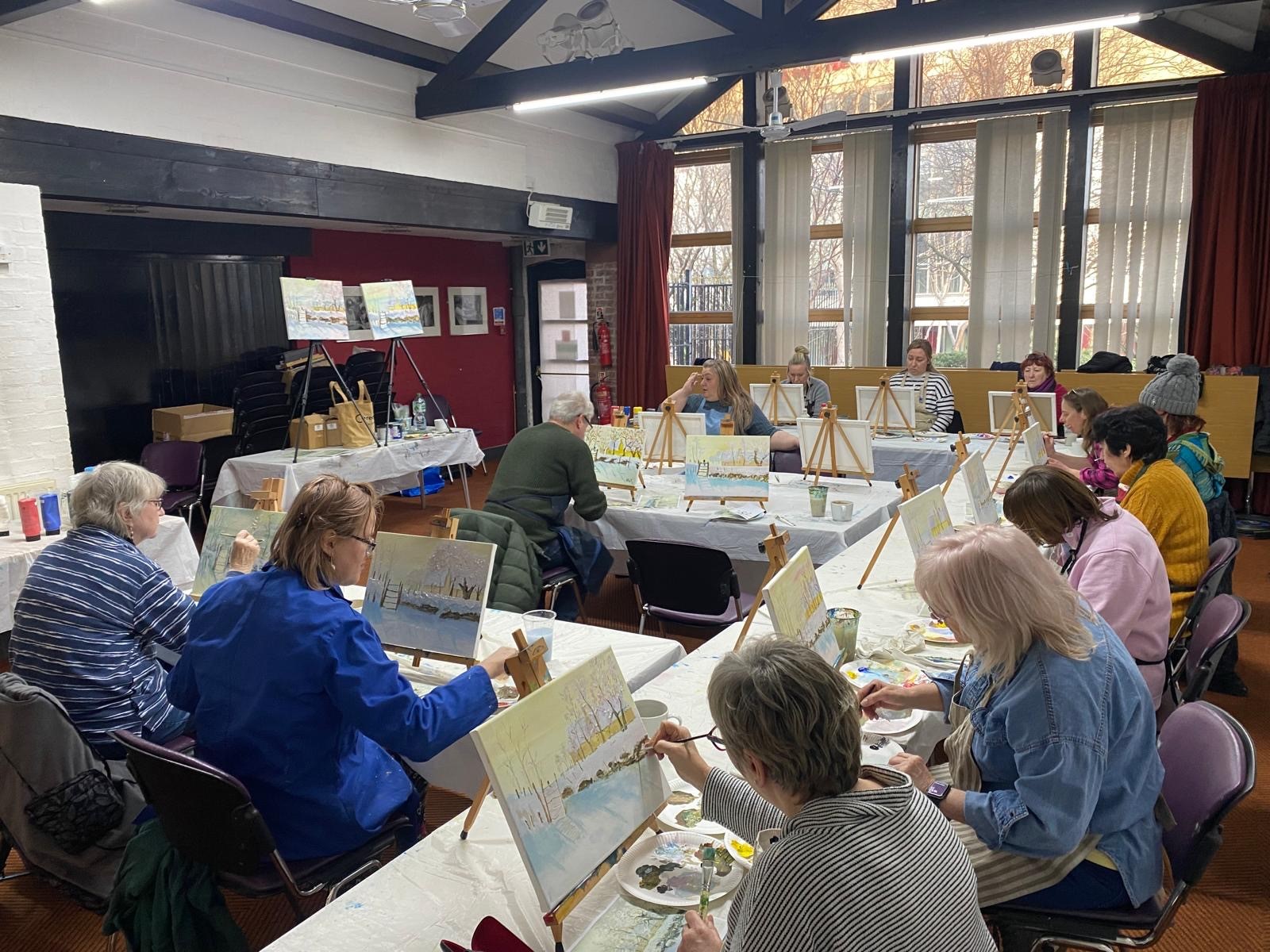 A classroom full of adults painting at easels