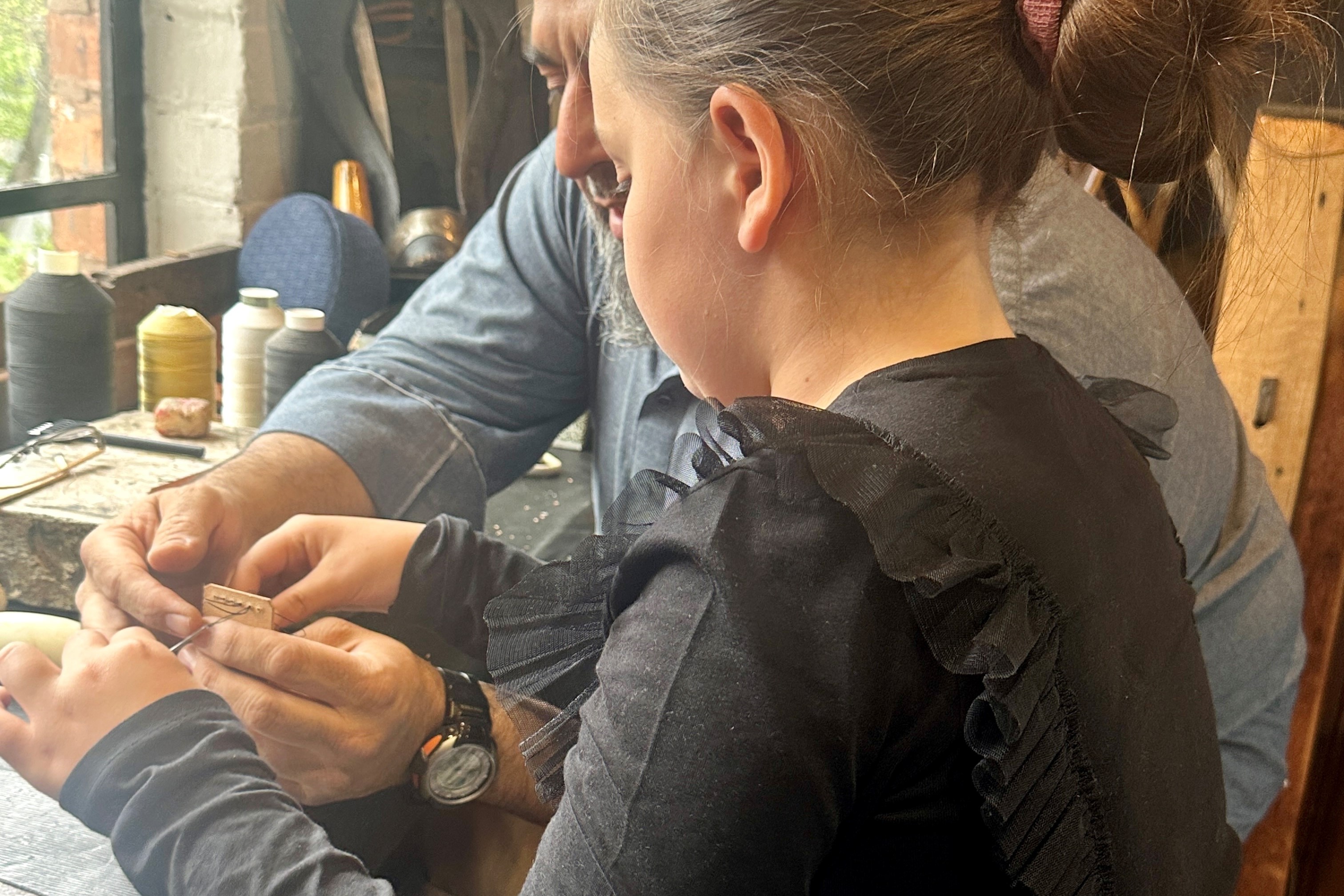 A young person learning how to stitch leather