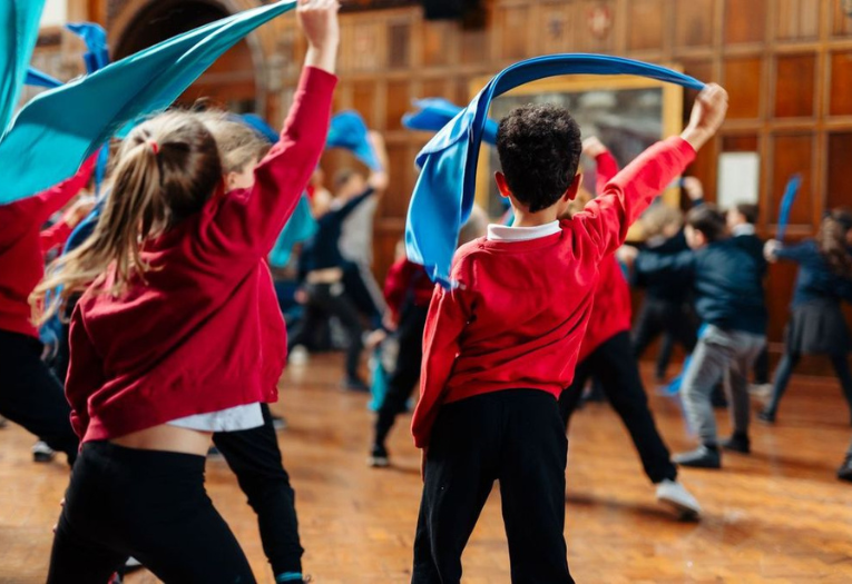 Children dancing holding fabric sashes aloft