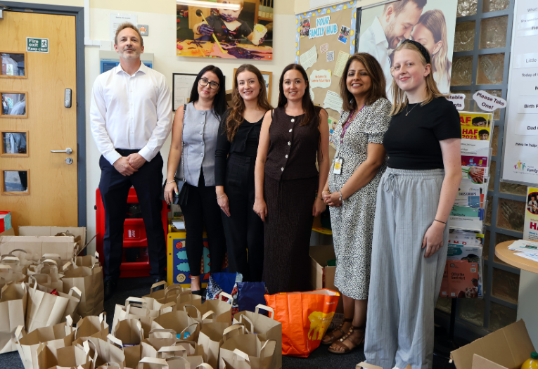 Image depicts employees from Opus and Walsall Council in front of food parcel bags.