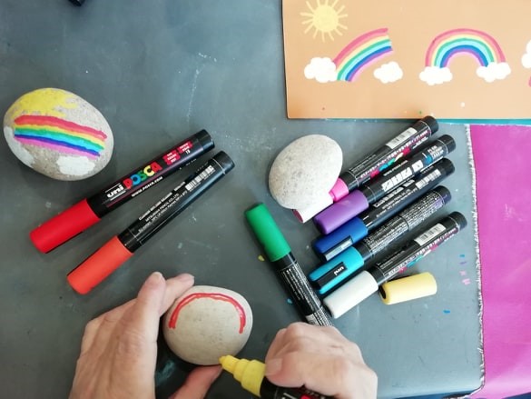 pens on a table with person drawing on a stone