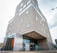 Exterior of the New Art Gallery Walsall, clad in pale terracotta tile with a steel and glass entrance