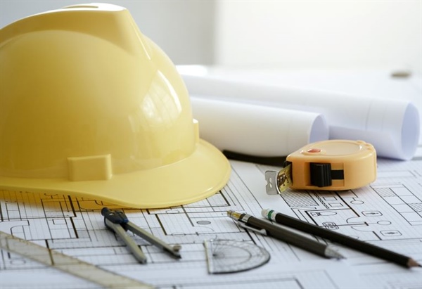 A yellow hard hat and some plans 