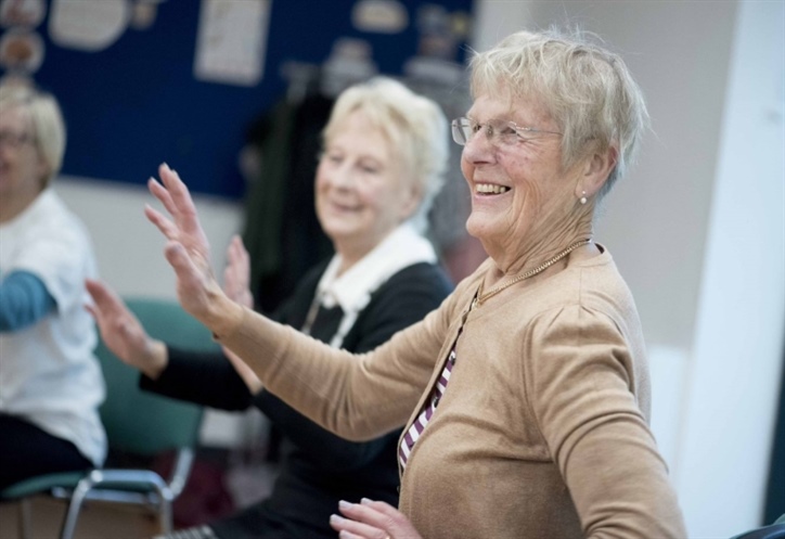 Older women taking part in a dance class while sitting down.