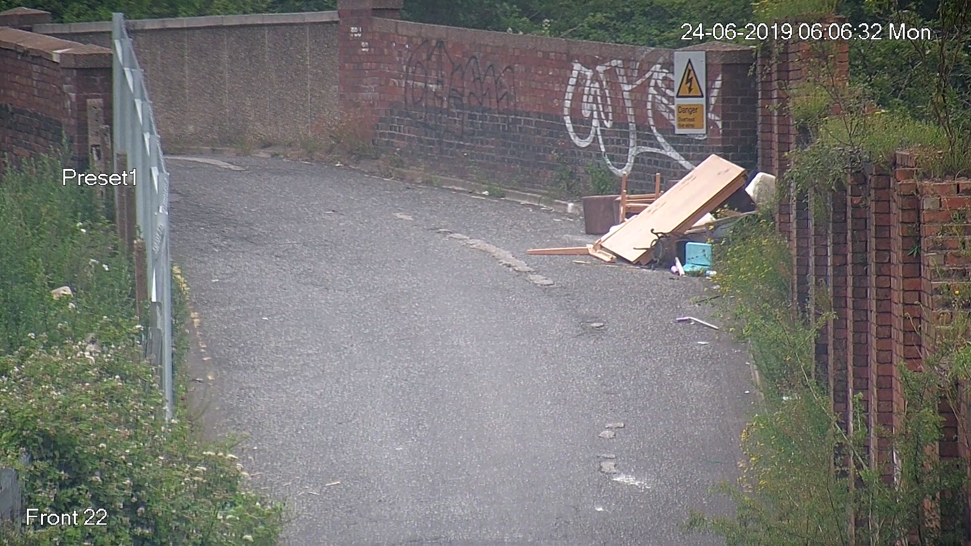 A screenshot of a CCTV image showing a road with fly tipped rubbish dumped to the side