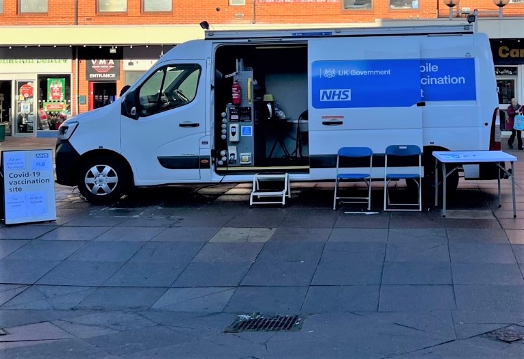 Image shows a mobile vaccination bus in a town centre.