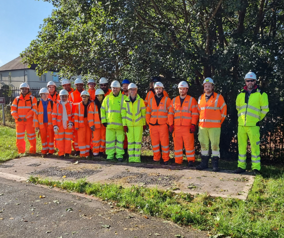 A group of contractors in high-visibility clothing stand together on a path in Willenhall