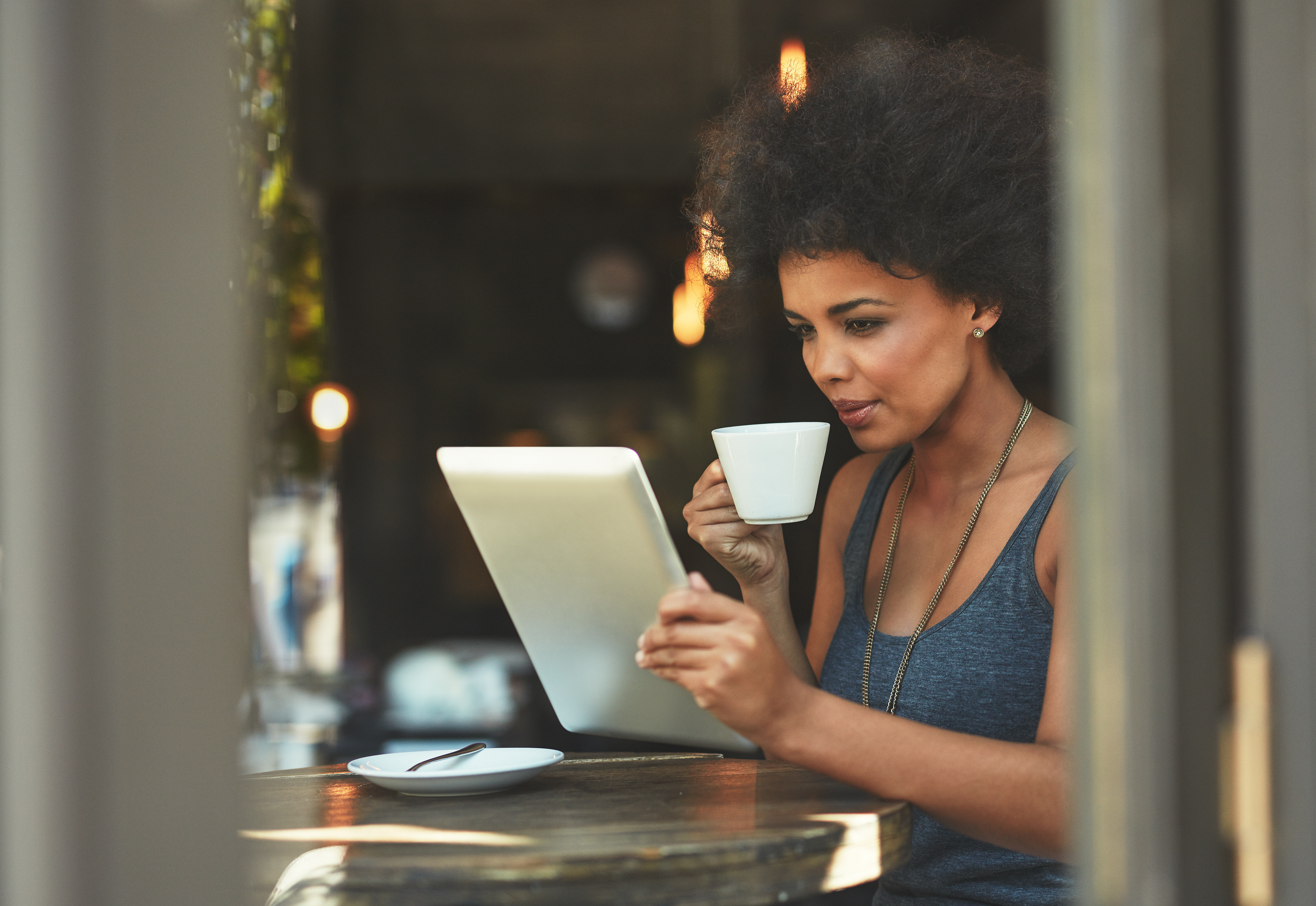 A woman reads from her tablet computer at a cafe