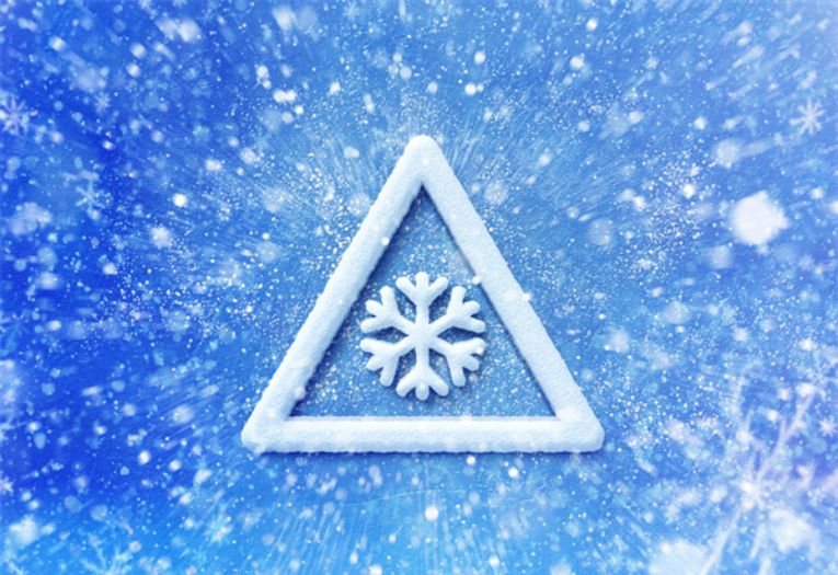 Image depicts a warning sign with a white snowflake against a blue and white background.
