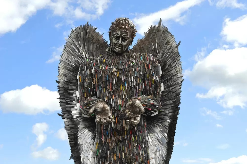 The Knife Angel, a sculpture of an angel made from blunted knives with a pained face, holding its hands out.