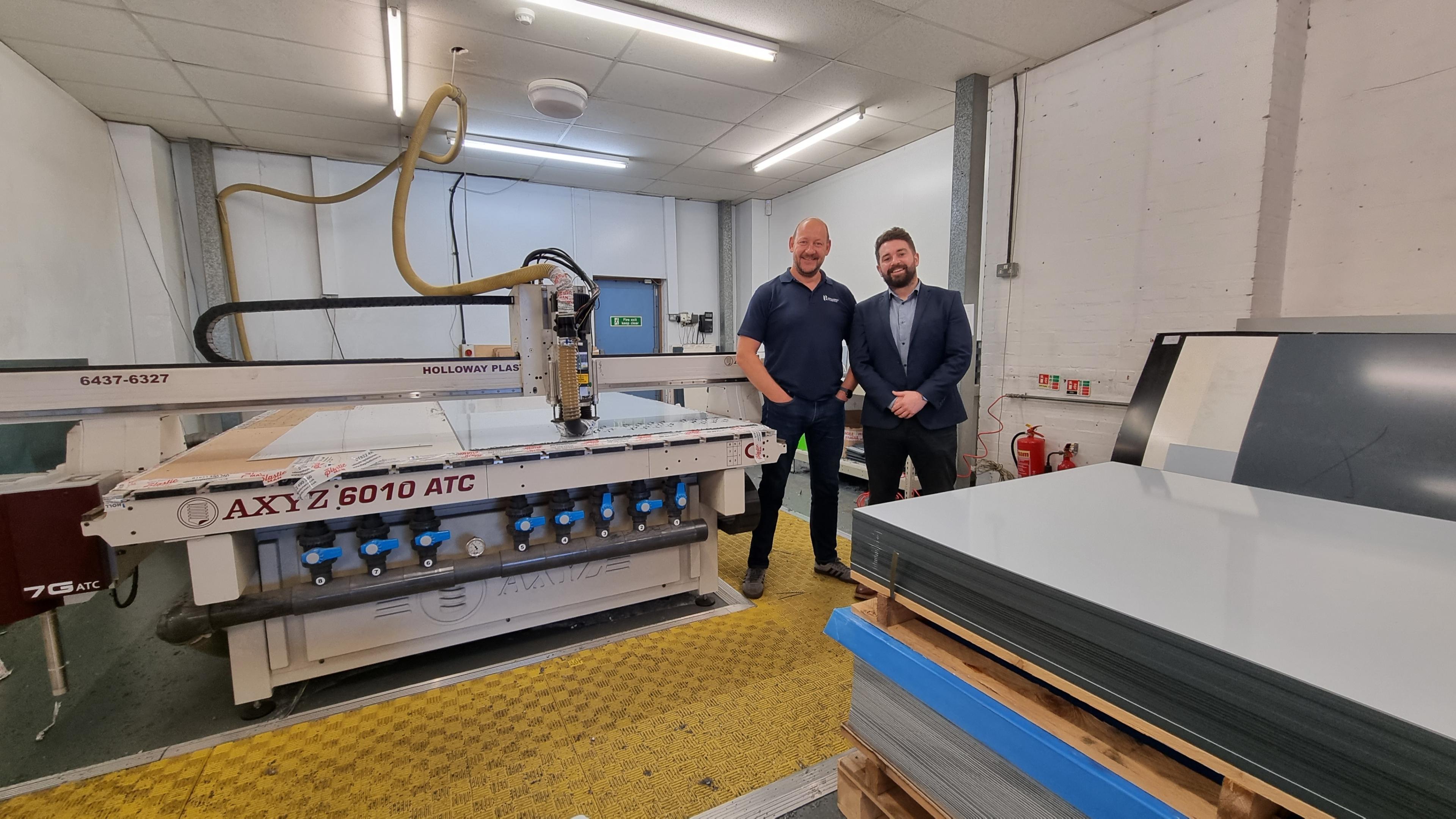 Two men standing next to a large CNC Router within a factory