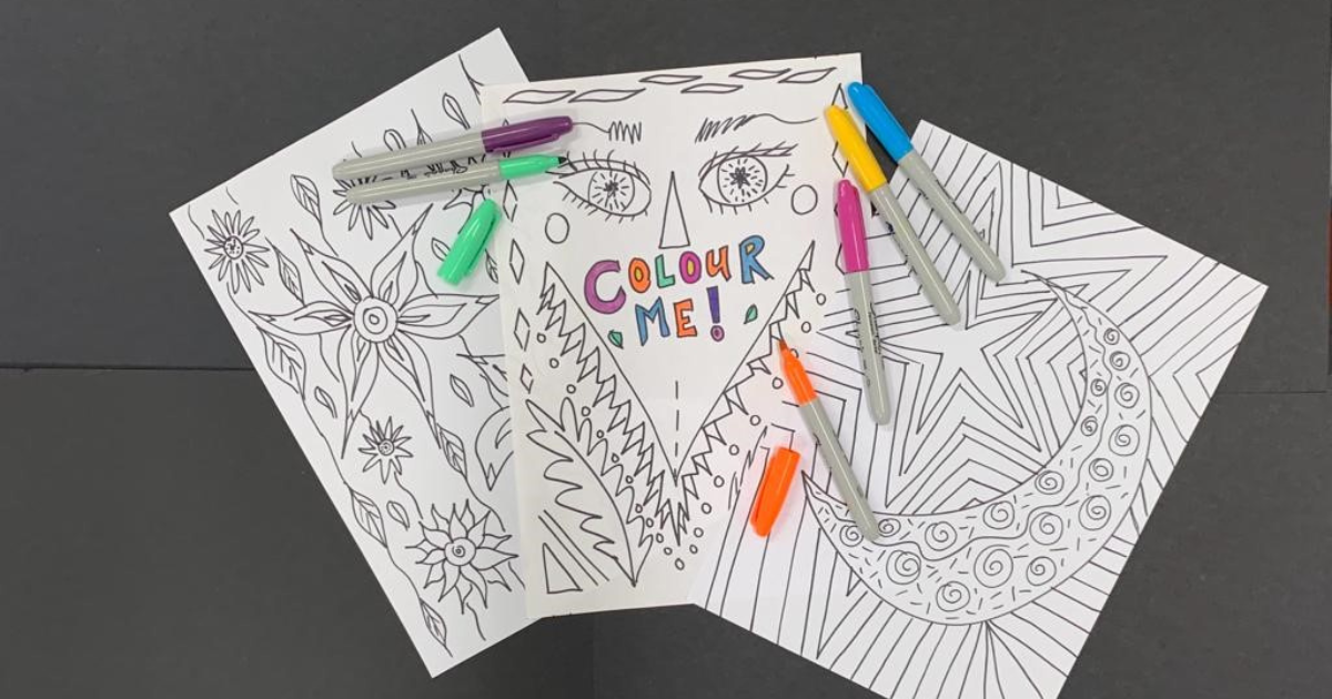 Three pieces of paper covered in patterns to colour in, different coloured marker pens sit on top of the paper. 