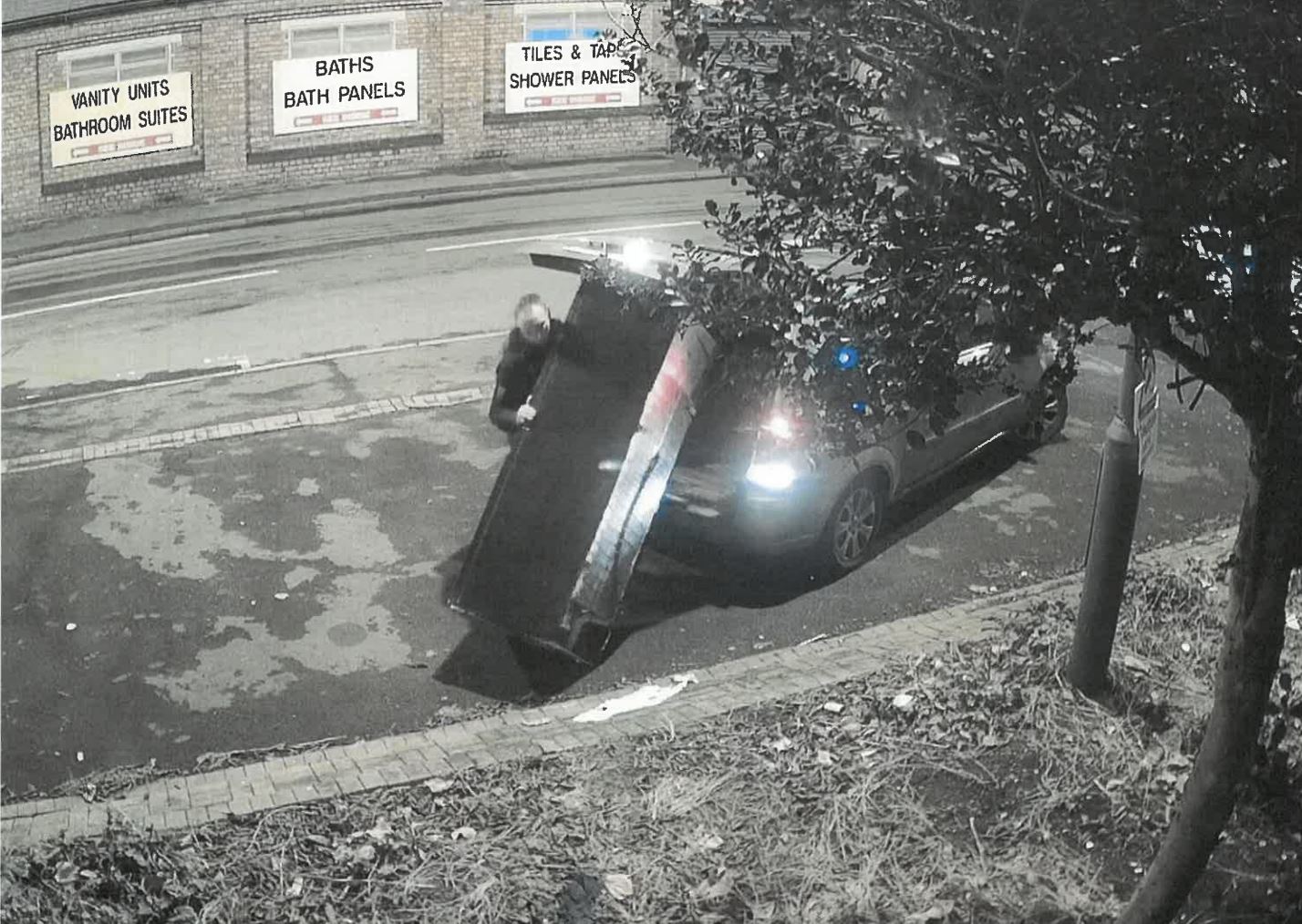 A still frame of CCTV footage where a man is fly-tipping a fridge at the side of a road.