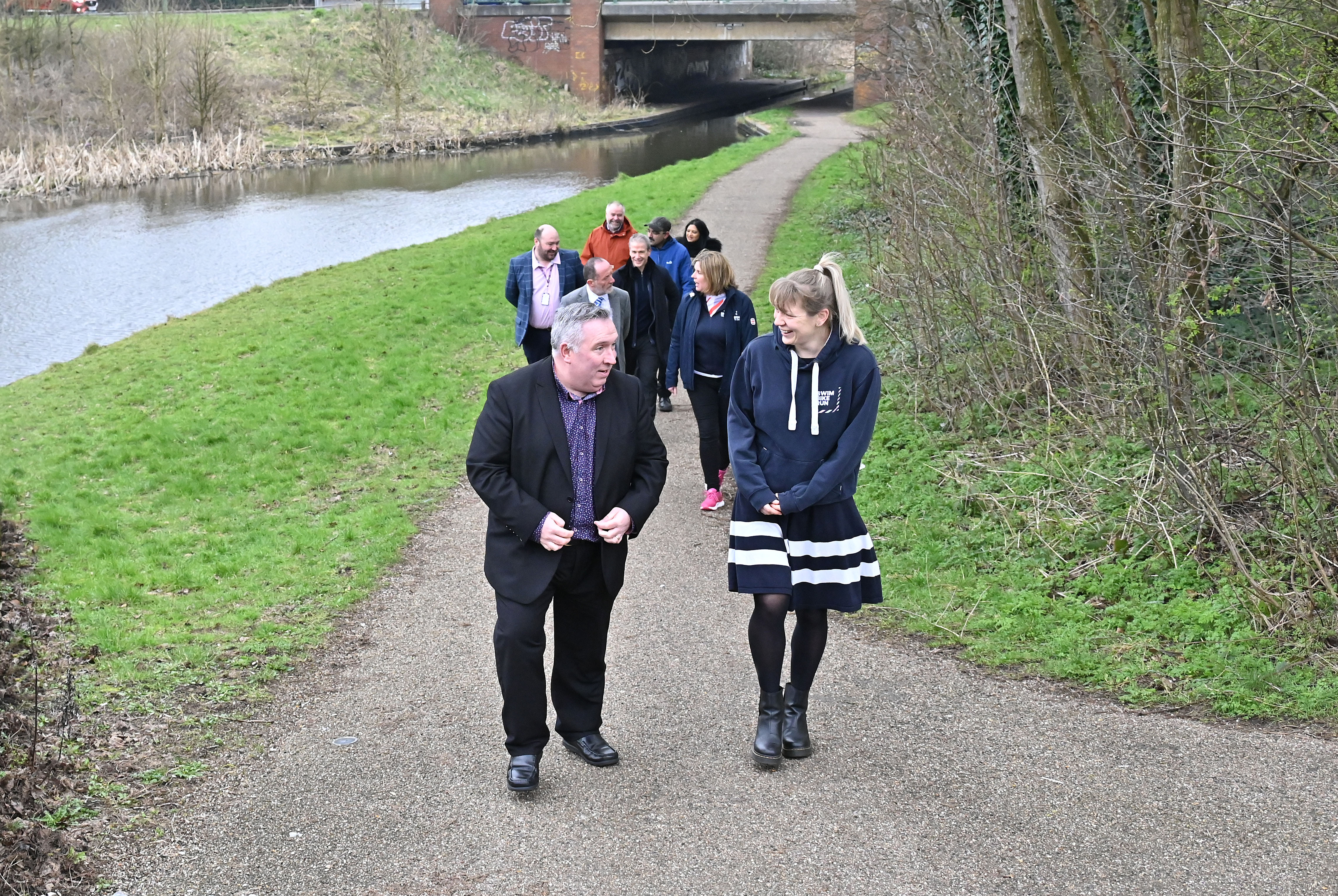A group of people walking along a canal towpath