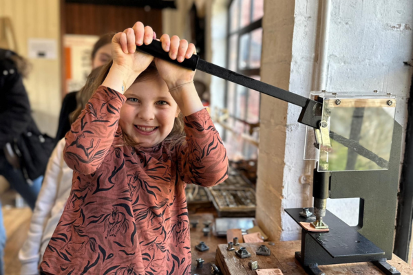 A child smiling at the camera and pushing a punch down.