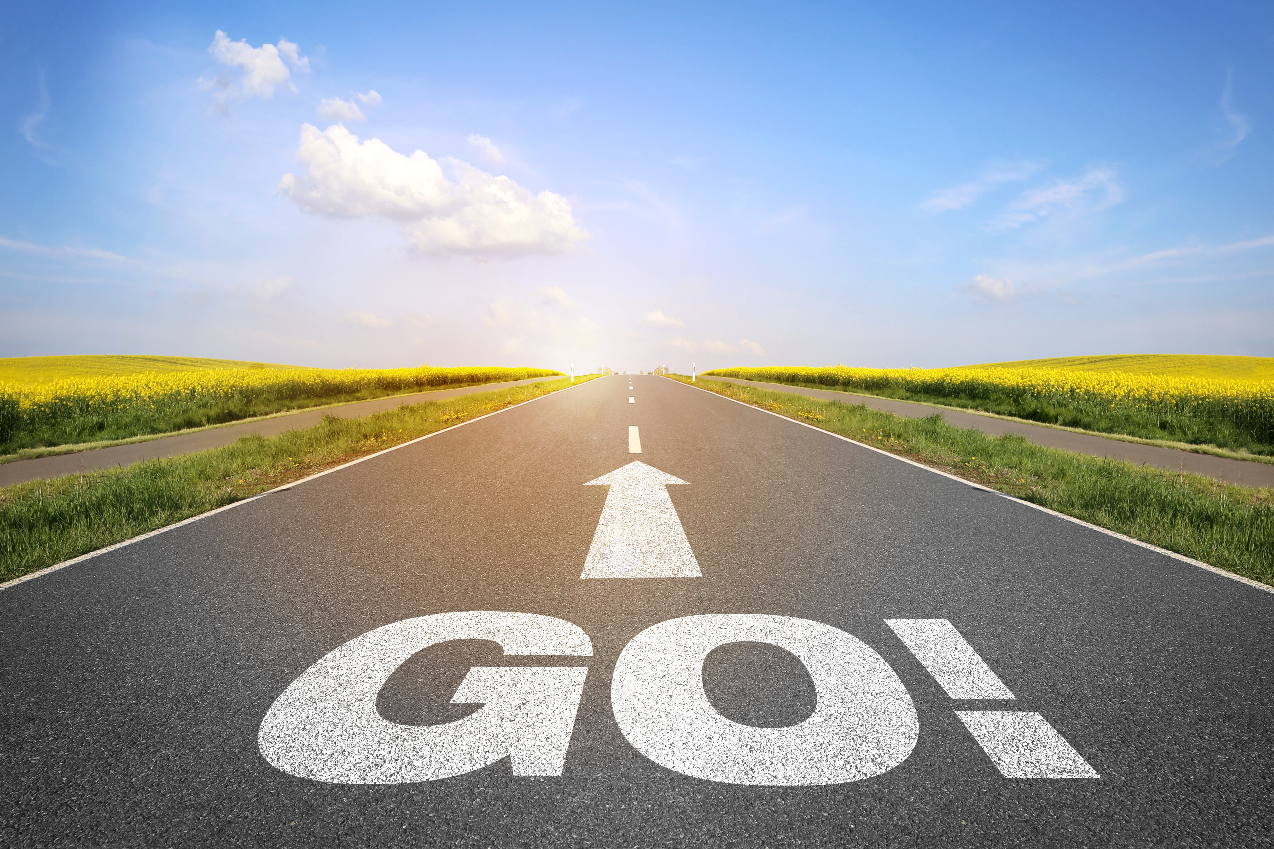 A tarmac road with GO and an arrow pointing ahead in white on the open road