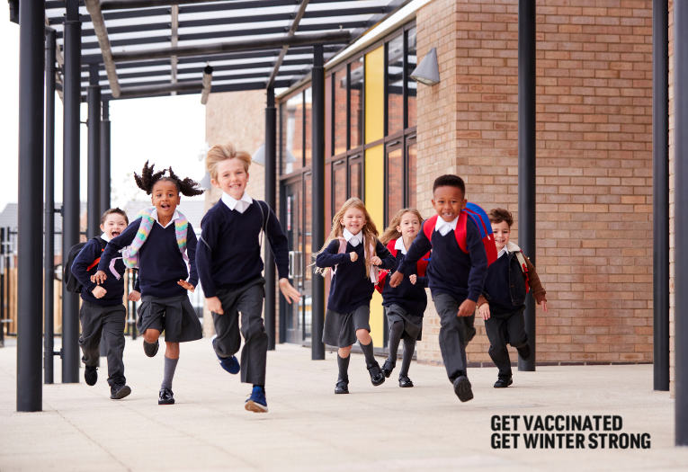 Image depicts a group of school children running in the playground. Text reads get vaccinated, get winter strong.