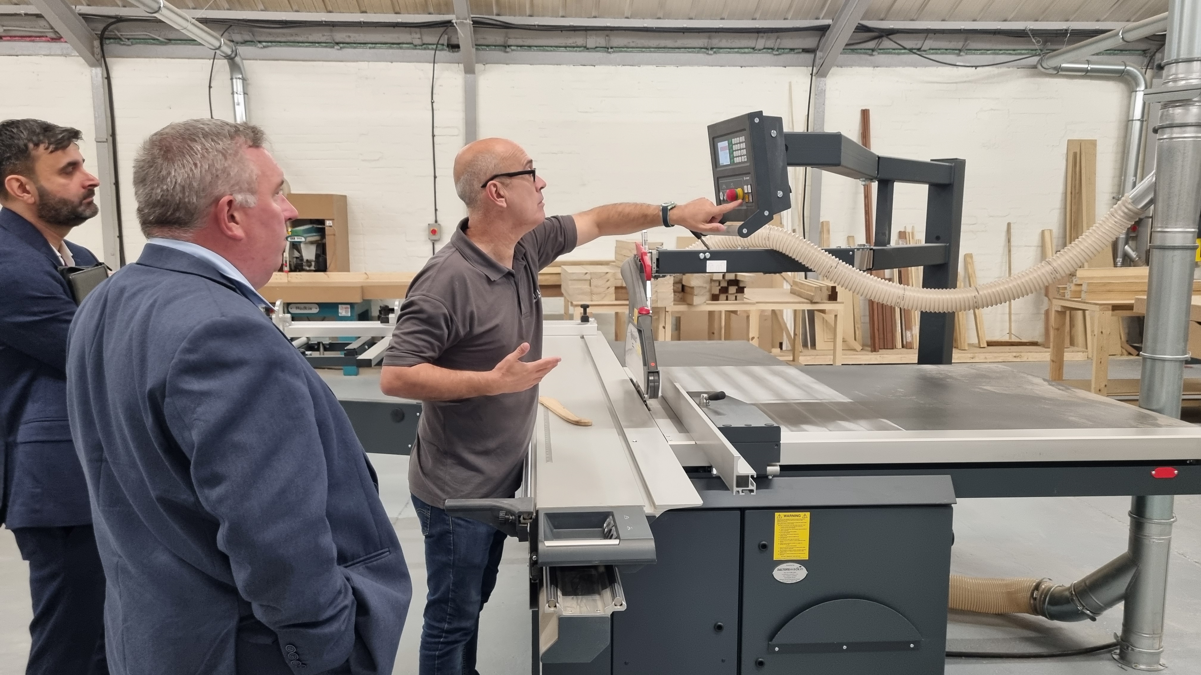 Three men look at a large piece of cutting equipment