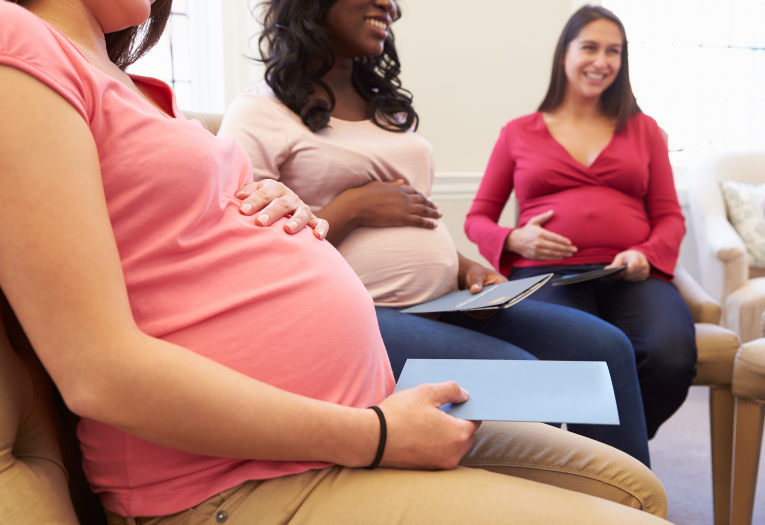 Image depicts a group of three pregnant women at an antenatal clinic.