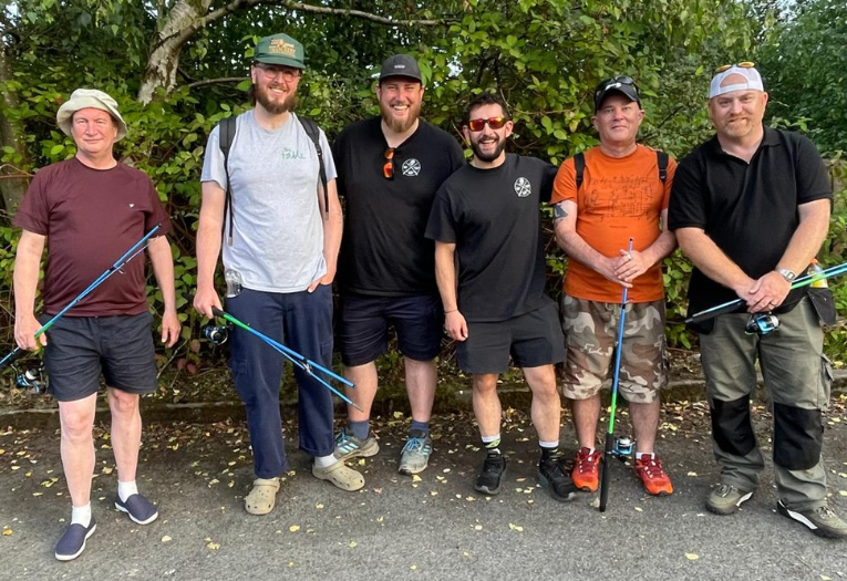 Image depicts six men in a group holding fishing equipment.