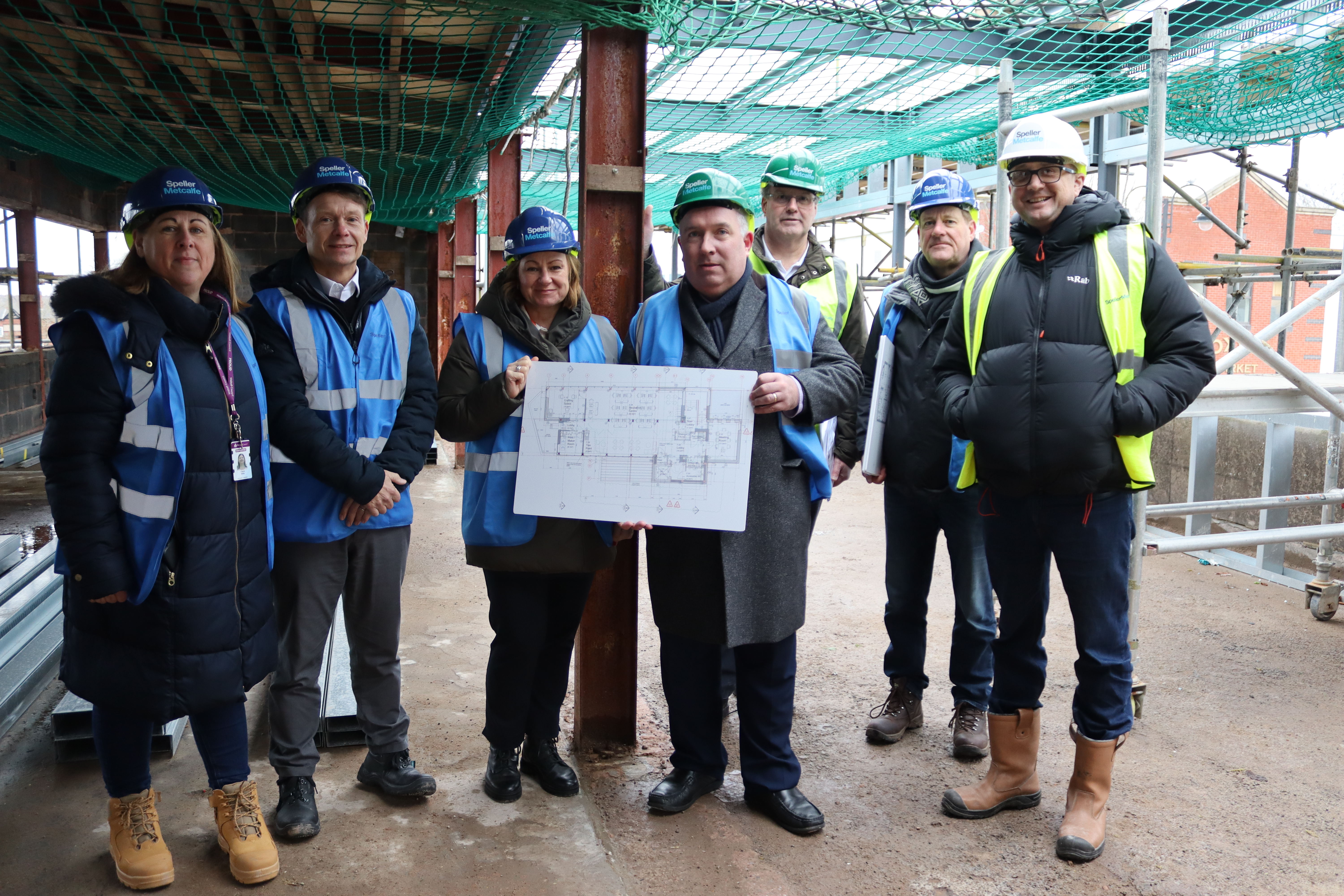 A group of people on a building site wearing high-vis jackets and hard hats