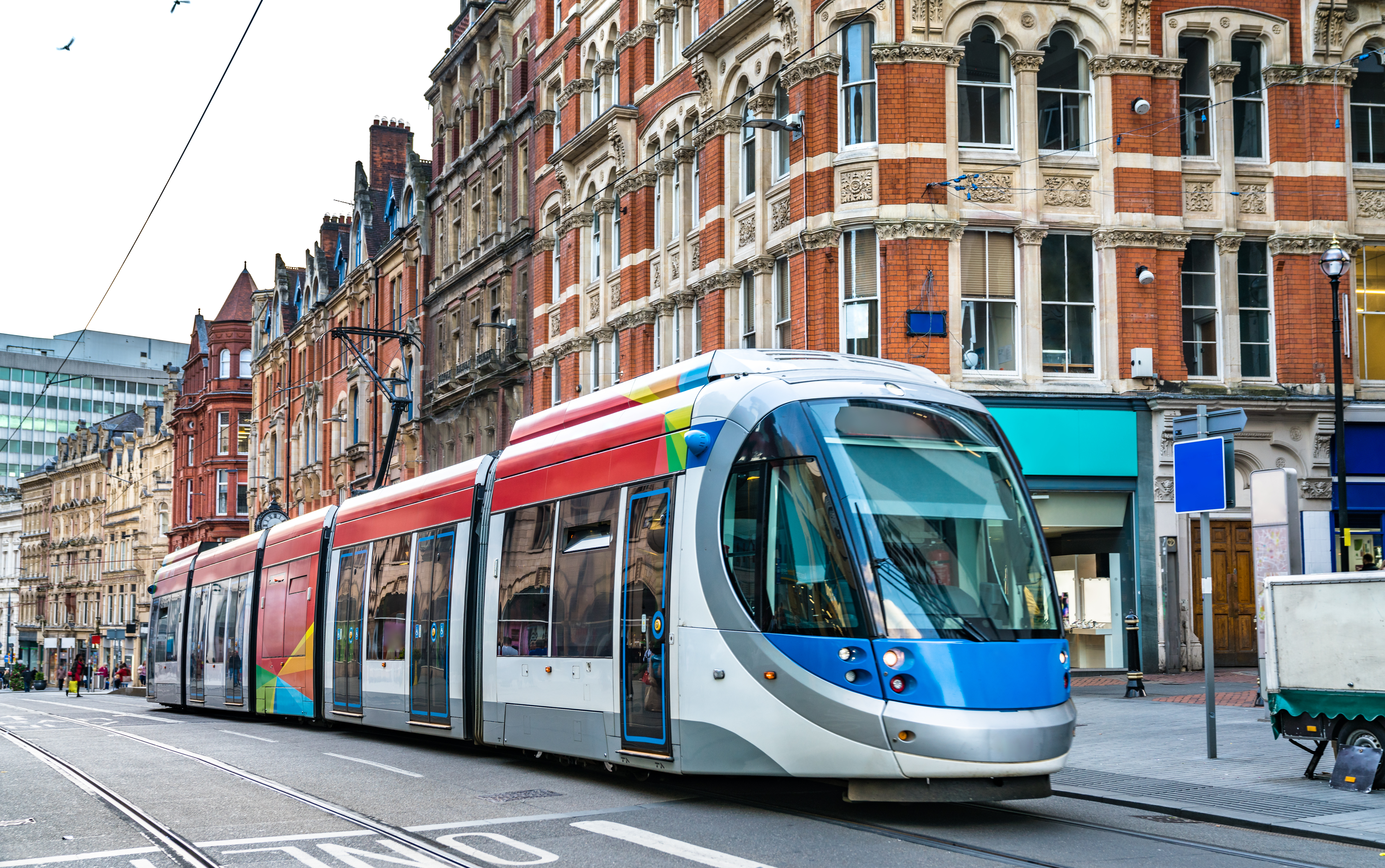 A tram is in a busy street in Birmingham city centre.