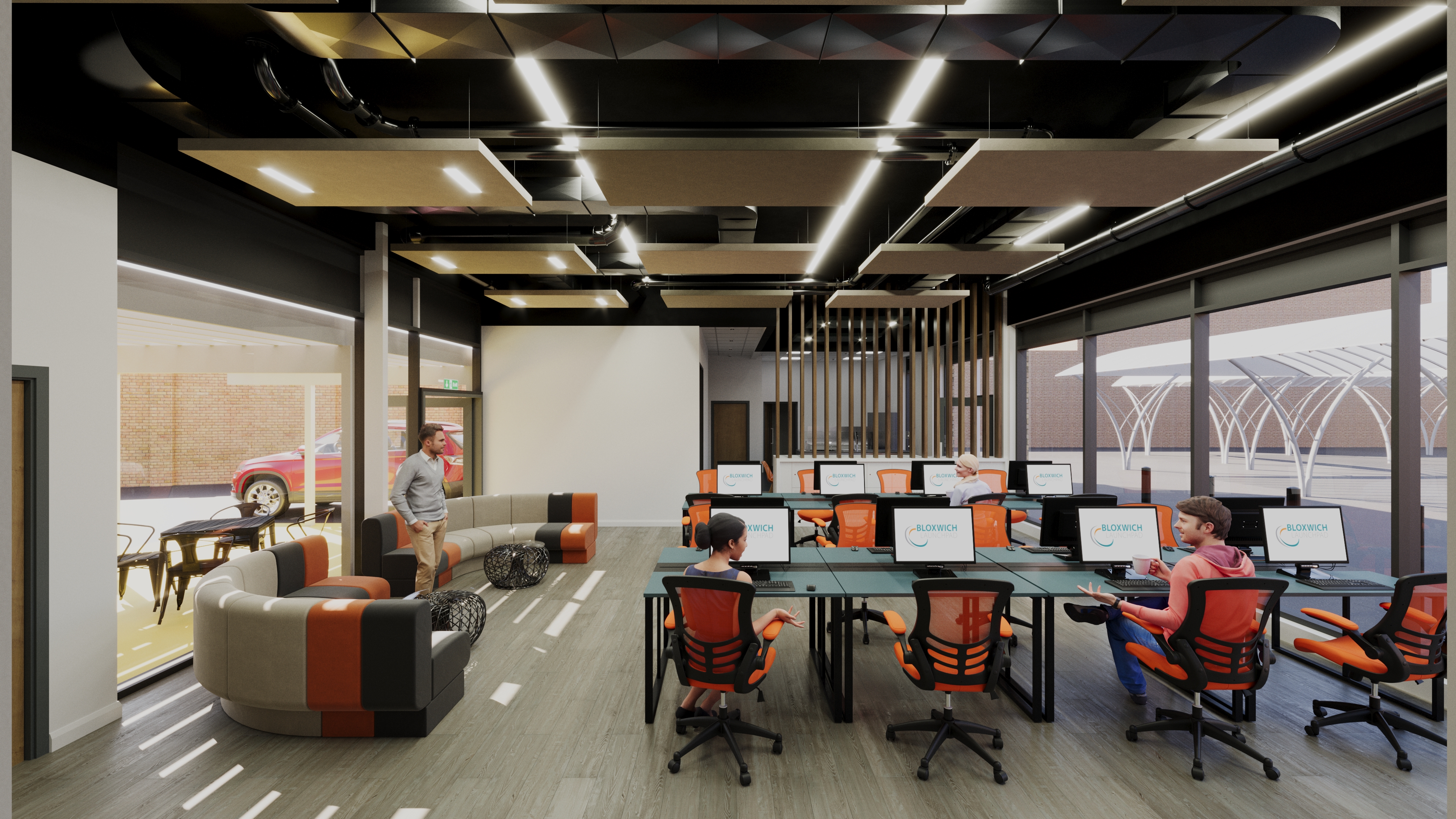 A bright modern office space with orange and grey seating and a bank of computers