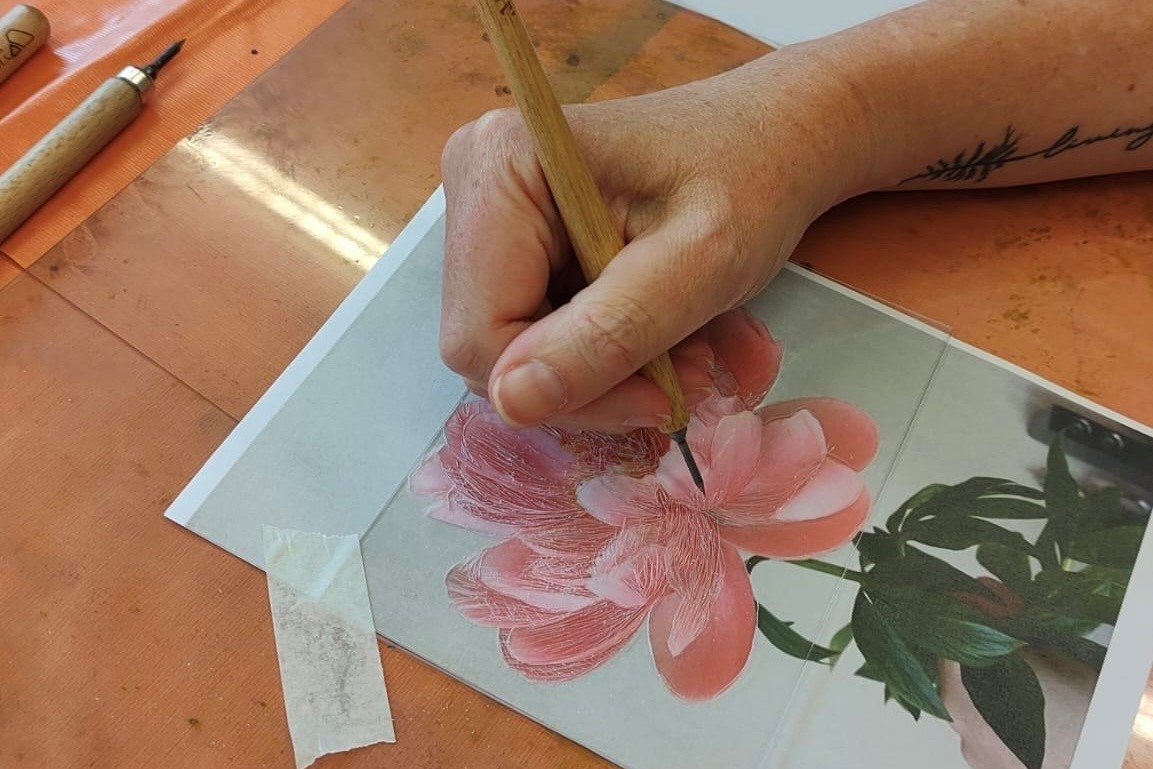 A person's hand creating an image of a pink flower