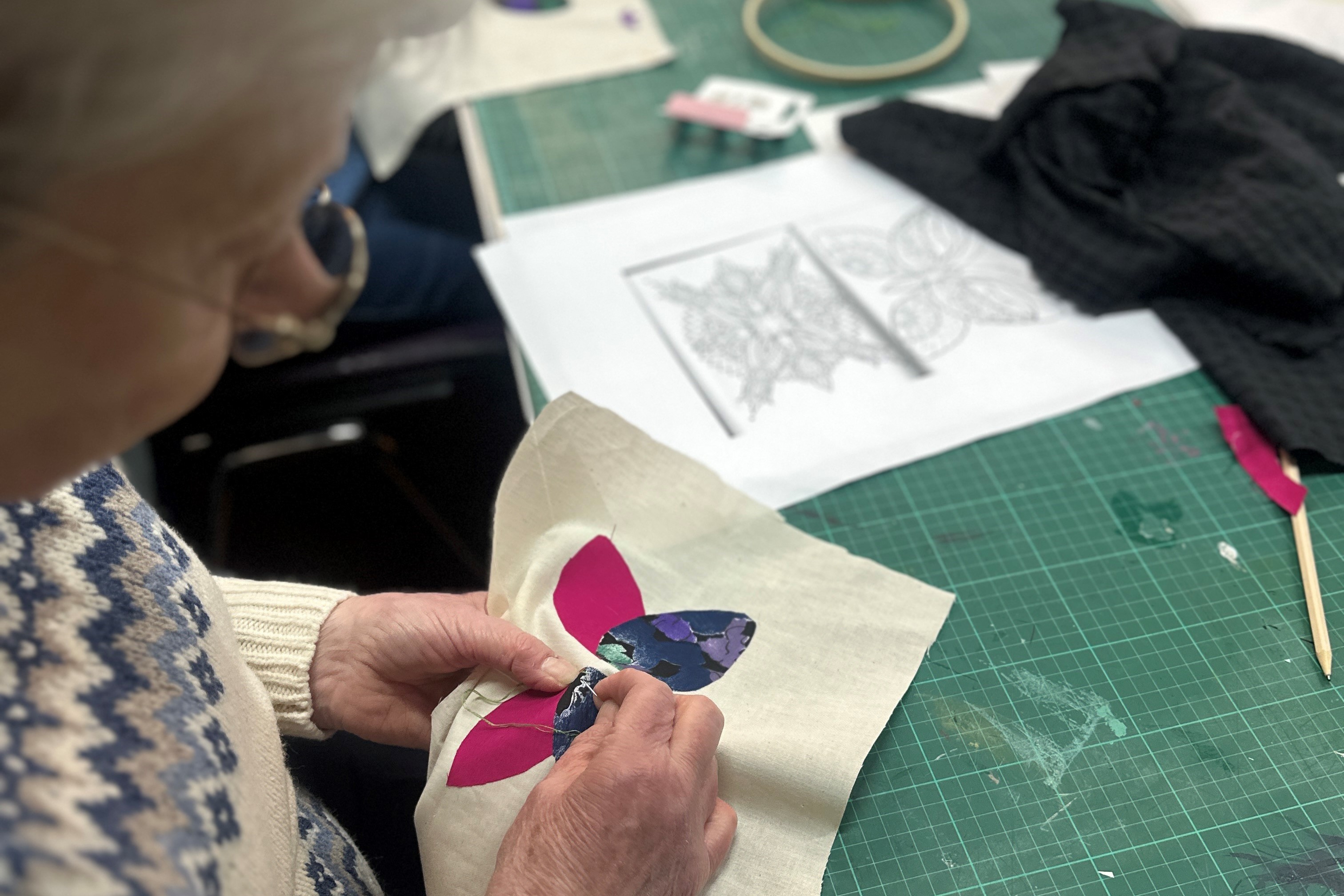 a woman sewing a flower on fabric