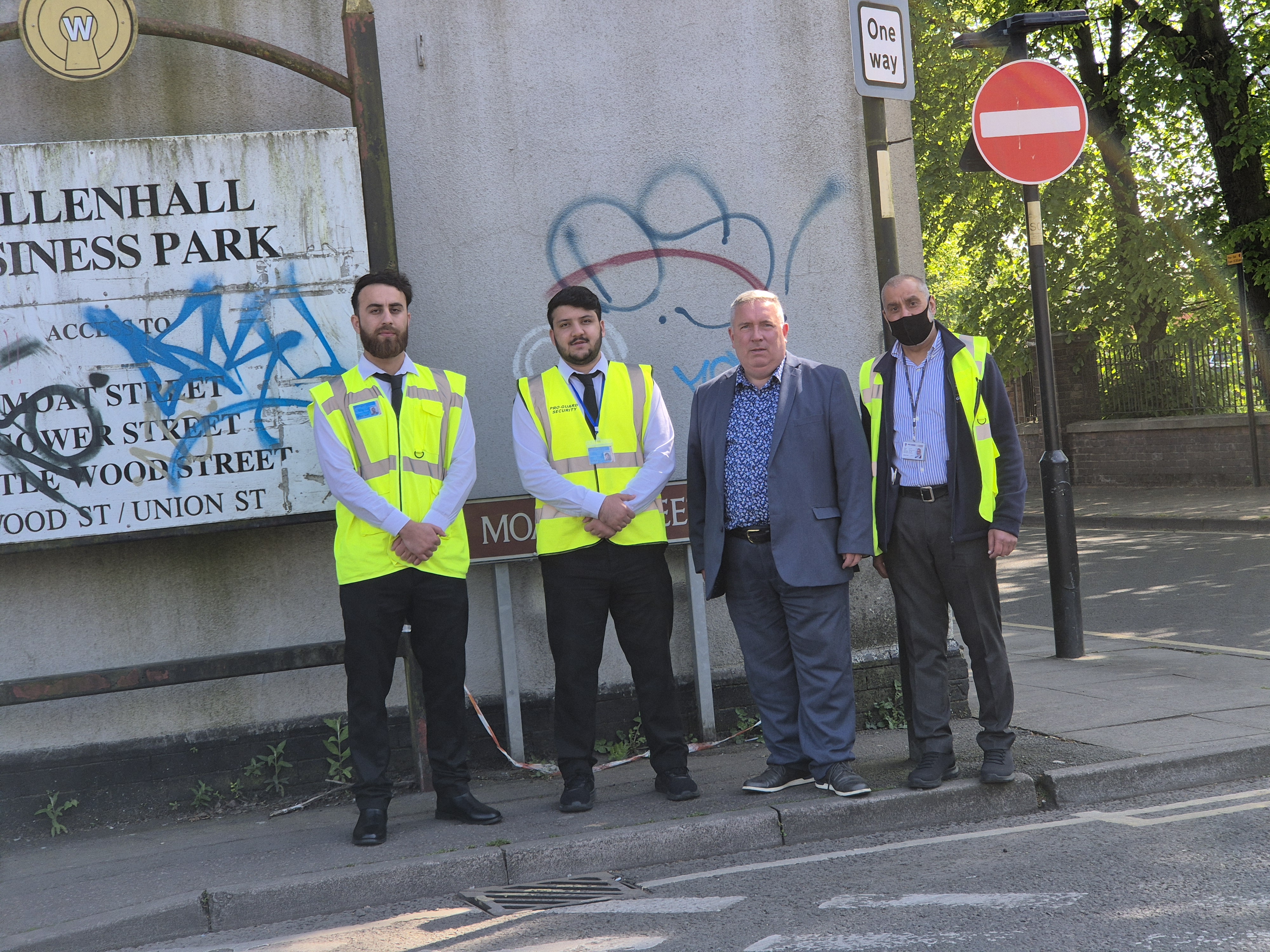 a group of four men standing beside a derelict factory
