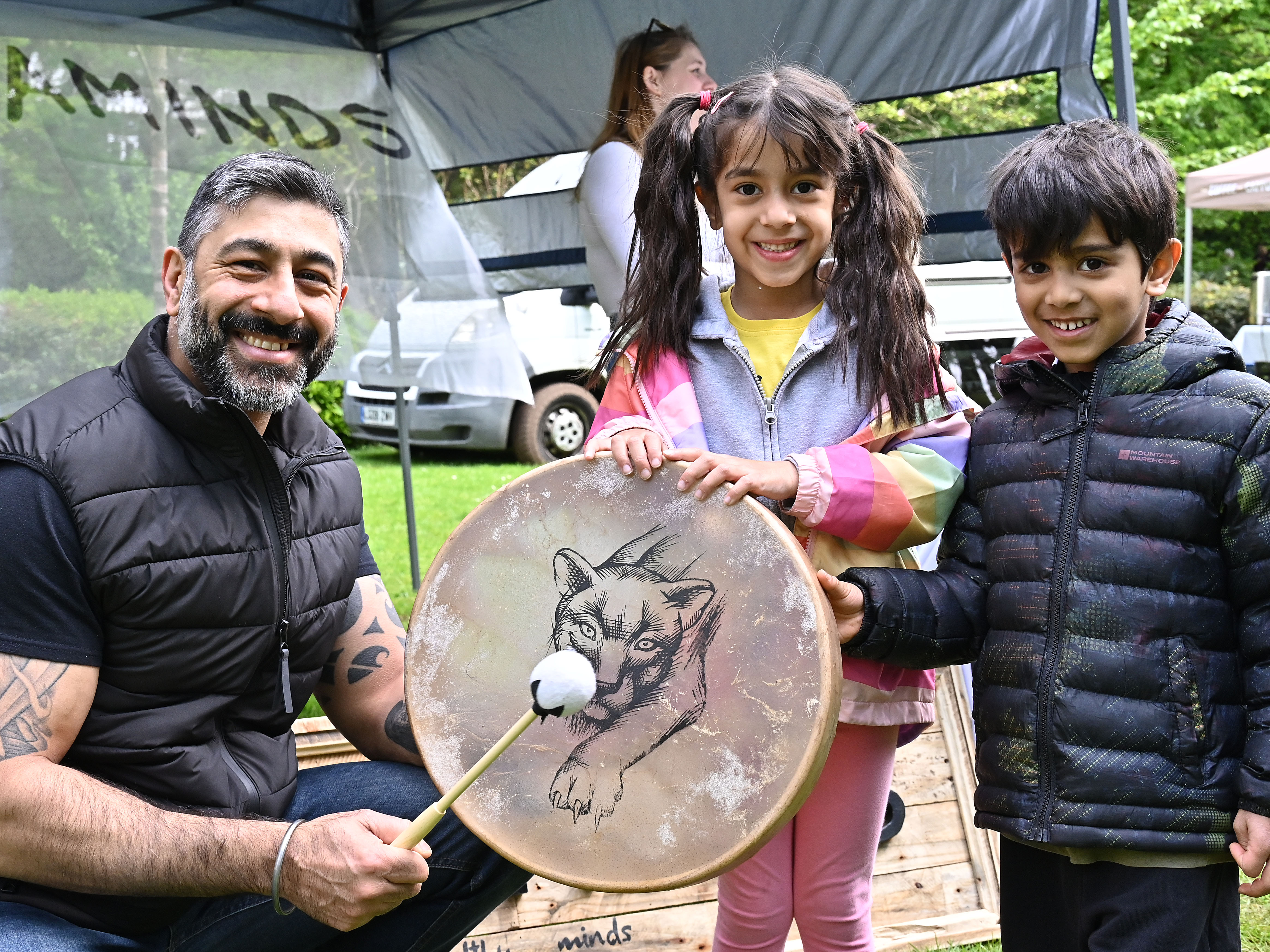 An adult holding a drum with two children