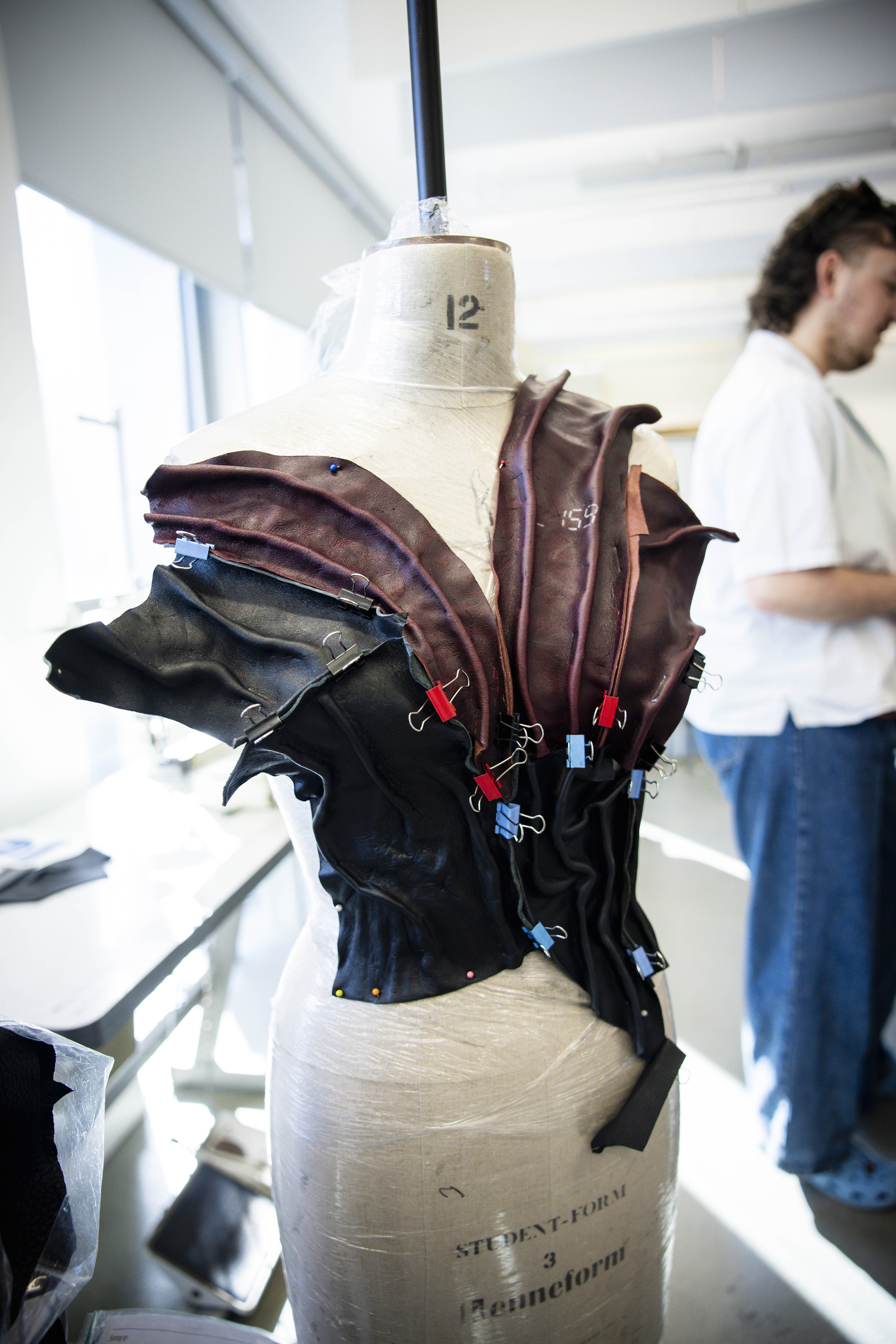 A mannequin with a leather garment pinned and clipped to it