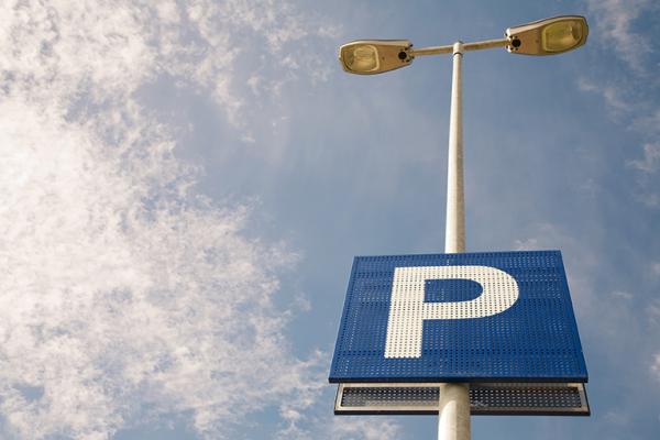 Blue parking sign on lampost with sky in the background