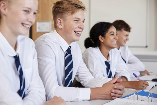 Teenagers smiling and  sitting at table in class 