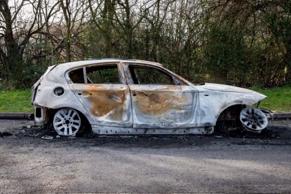 A rusted abandoned car on the street. 