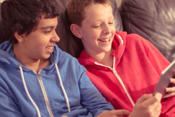 two tweens watching a tablet together