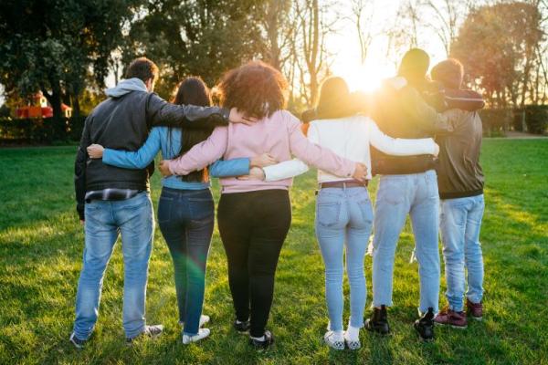 Group of 6 teenagers standing outdoors embracing