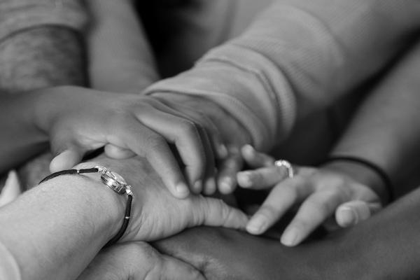 Close up of a group of people, each placing a hand on top of another person's hand