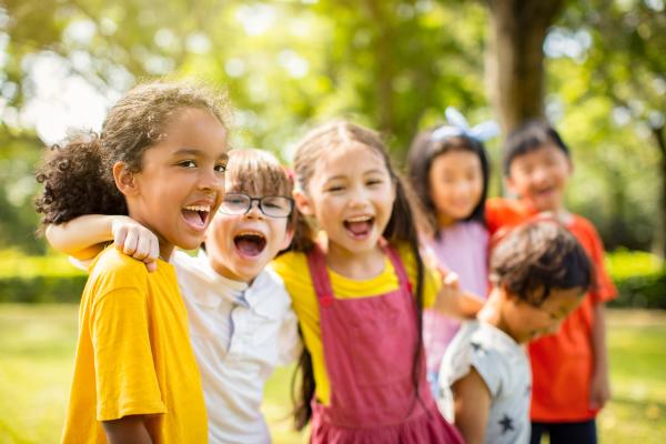 A group of children smiling with their arms on each others shoulders