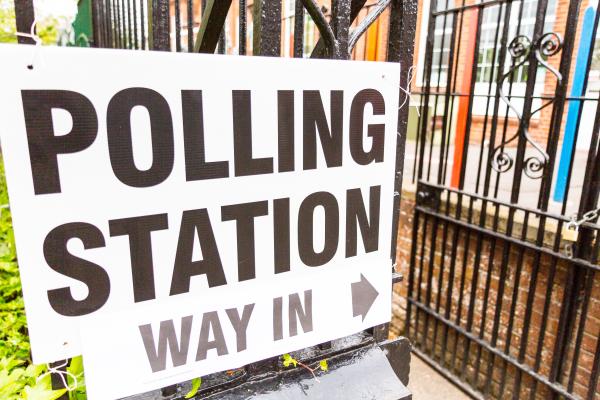 Polling station sign attached to railings outside a building