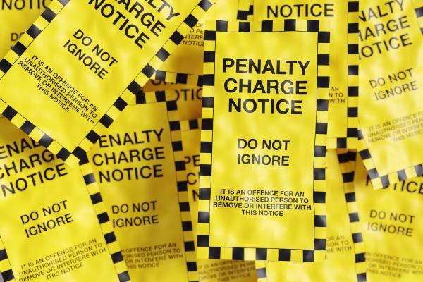 Yellow and black penalty charge notices in a small pile