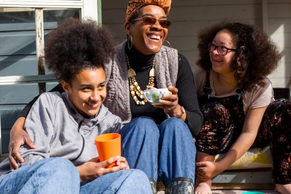 Woman with two teenage girls, sitting outside drinking coffee together