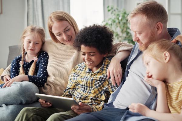 fostering family looking at tablet on the sofa with three children