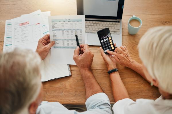 A couple using a calculator and laptop to work out their bills and payments