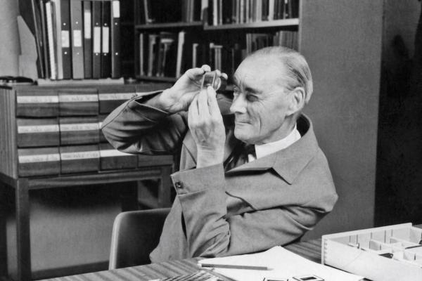 A researcher in the archives, viewing a slide through a magnifying glass in 